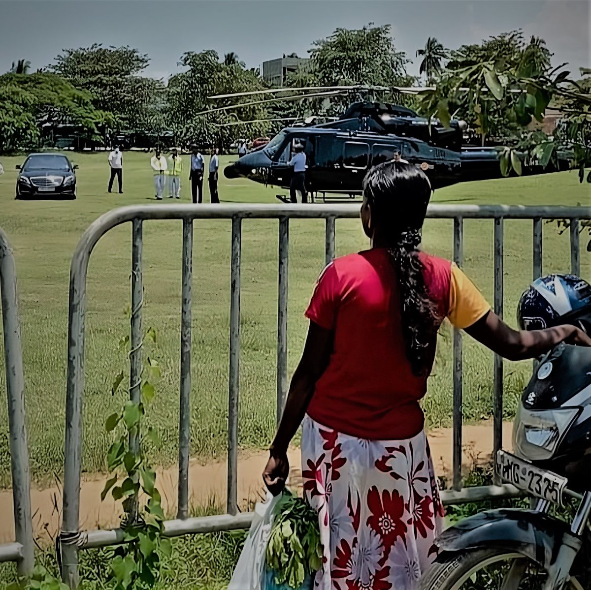 officiallahiru's tweet photo. A poor woman with some plants in her bag eyeing up a VIP who's hopped off a chopper into a Merc. The gap is profound, between the rich and the poor in 🇱🇰. She may be wondering why fate's been so unfair, why some have loads while others have bugger all. #lka https://t.co/o7TEsyx9jr