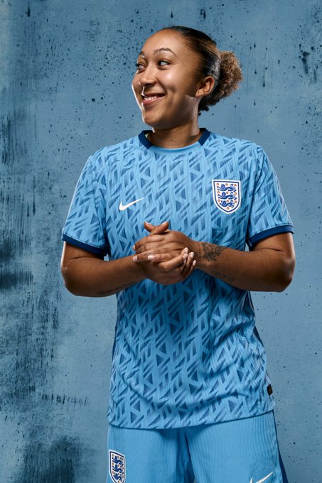 Lauren James poses in the England away kit, against a blue backdrop.