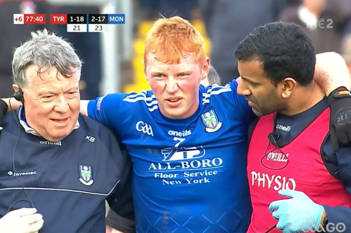 Two men lifting Ryan O'Toole off the field because his balls are too big for one man to carry