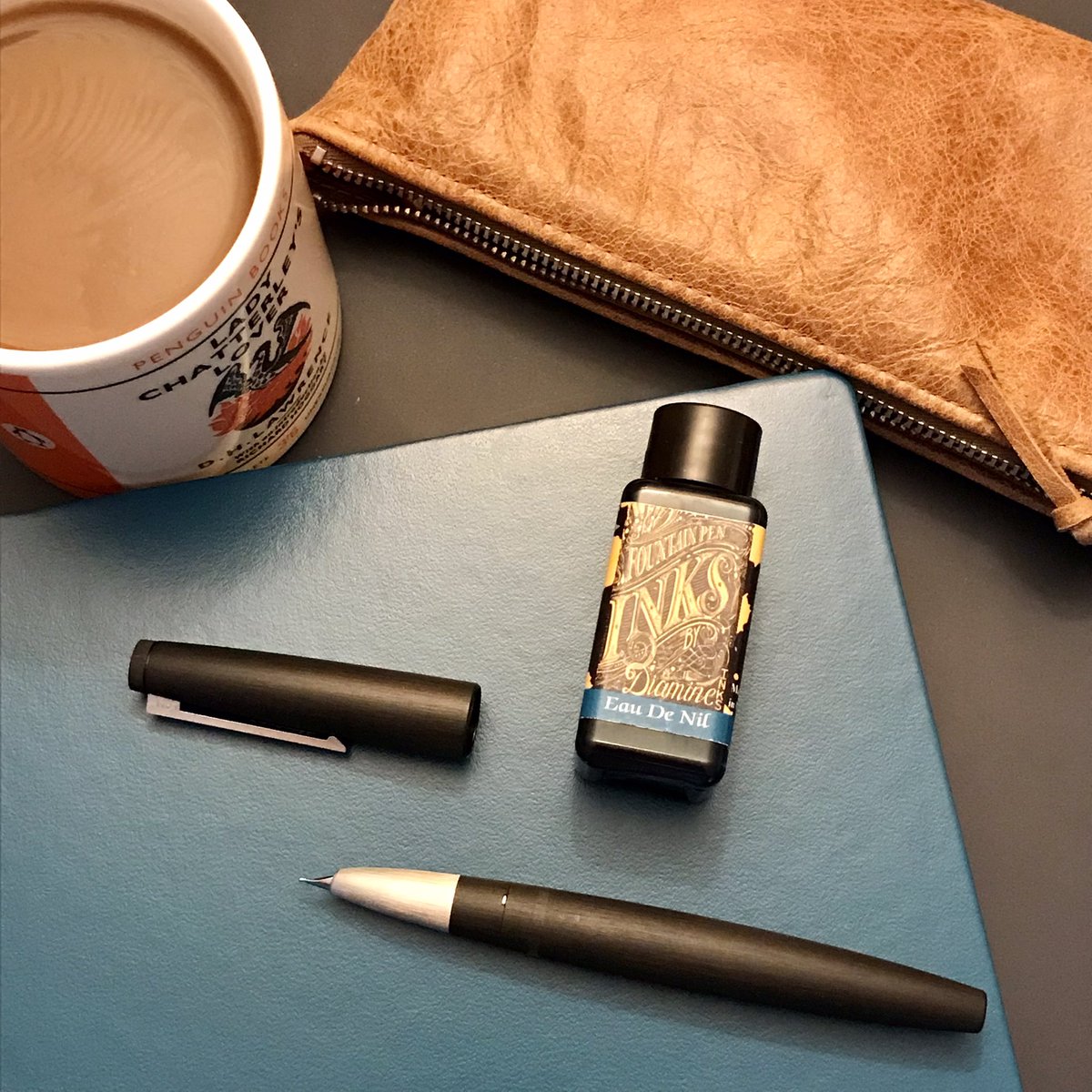 TomGMann's tweet photo. Ok, brand new @LT1917UK notebook, LAMY 2000 fountain pen, Diamine Eau de Nil ink, coffee in a Penguin Classic mug… so I’m pretty much guaranteed to get some great writing done today, yeah…? 
#amwriting @PurePens #WritingCommunity https://t.co/n5mEUNECgi
