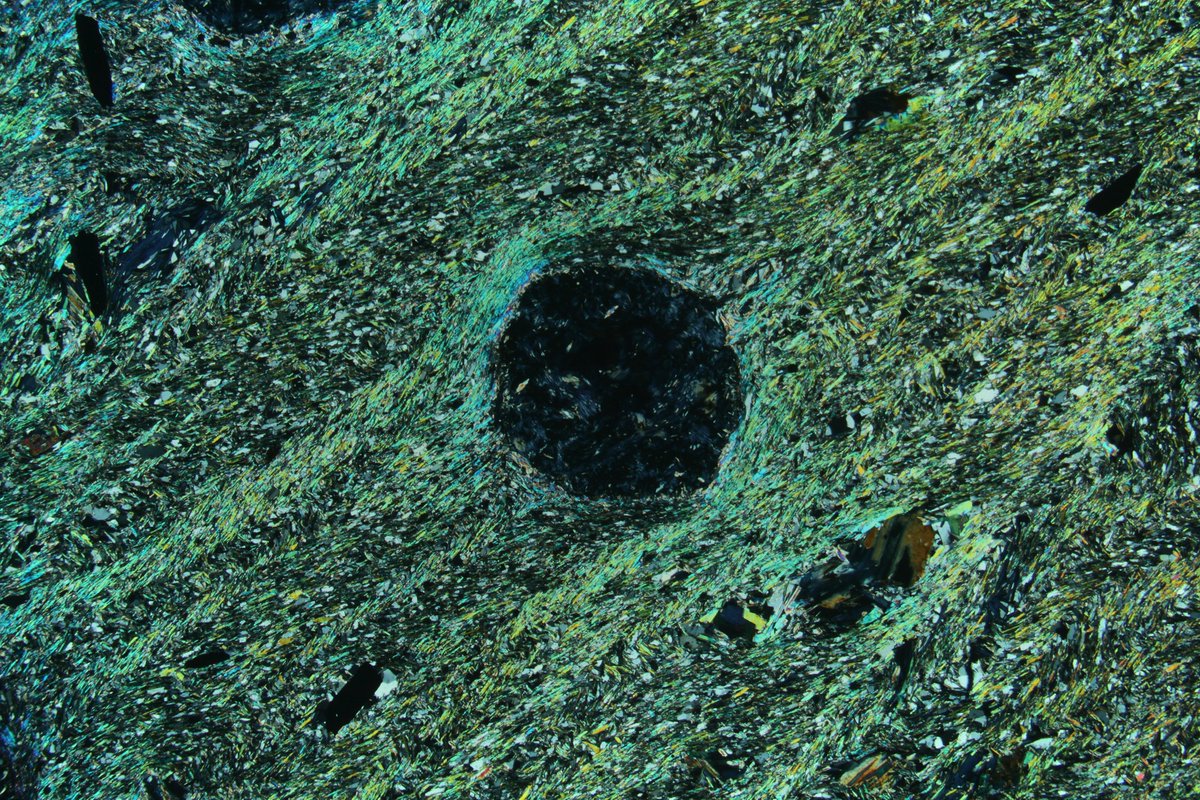 SpectrumPetro's tweet photo. Garnet porphyroblast replaced by pennanite (blue in XPL and green in PPL) with relic radioactive mineral damage (dark spots).

#spectrumpetro #thinsectionthursday #thinsection #geology #mineralogy #science #nature #Minerals #mineral #science #rocks #petrography https://t.co/48lZnY7CsX
