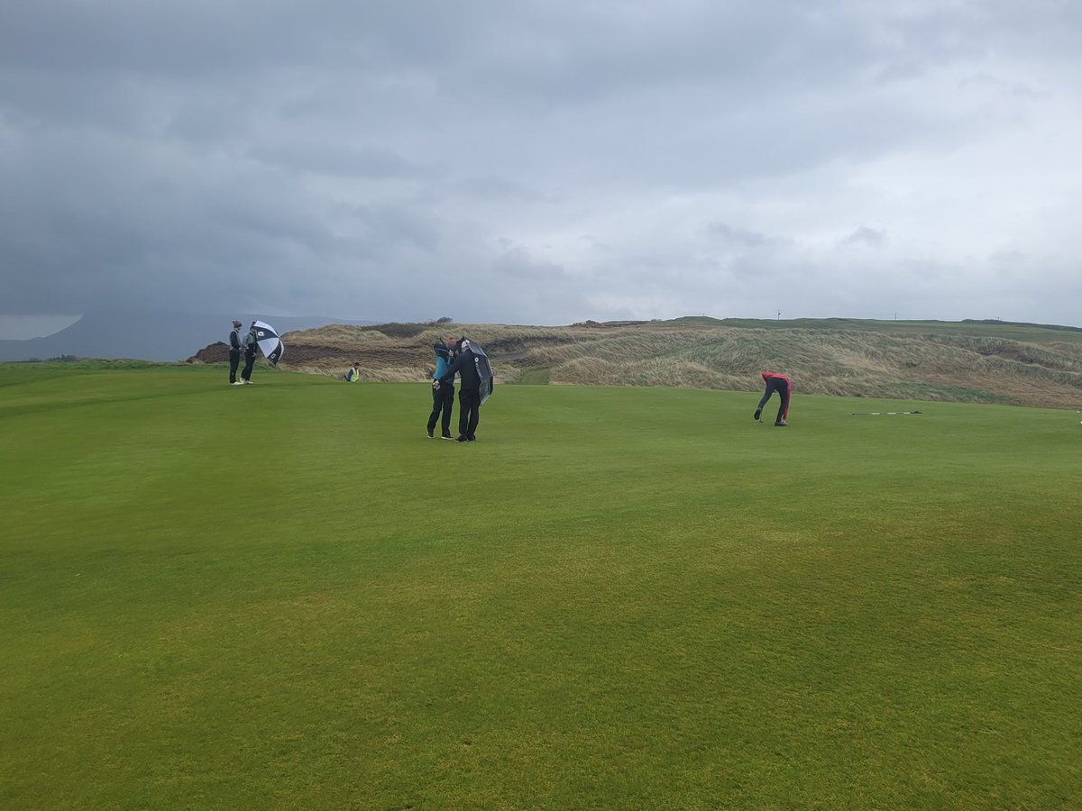 Magoo462's tweet photo. The angle of the umbrellas tells you all you need to know about conditions @CountySligoGC as James Claridge picks his ball out of the hole on the 4th as the new tournament leader @IrishGolferMag @GolfIreland_ https://t.co/mvcydEcHeg