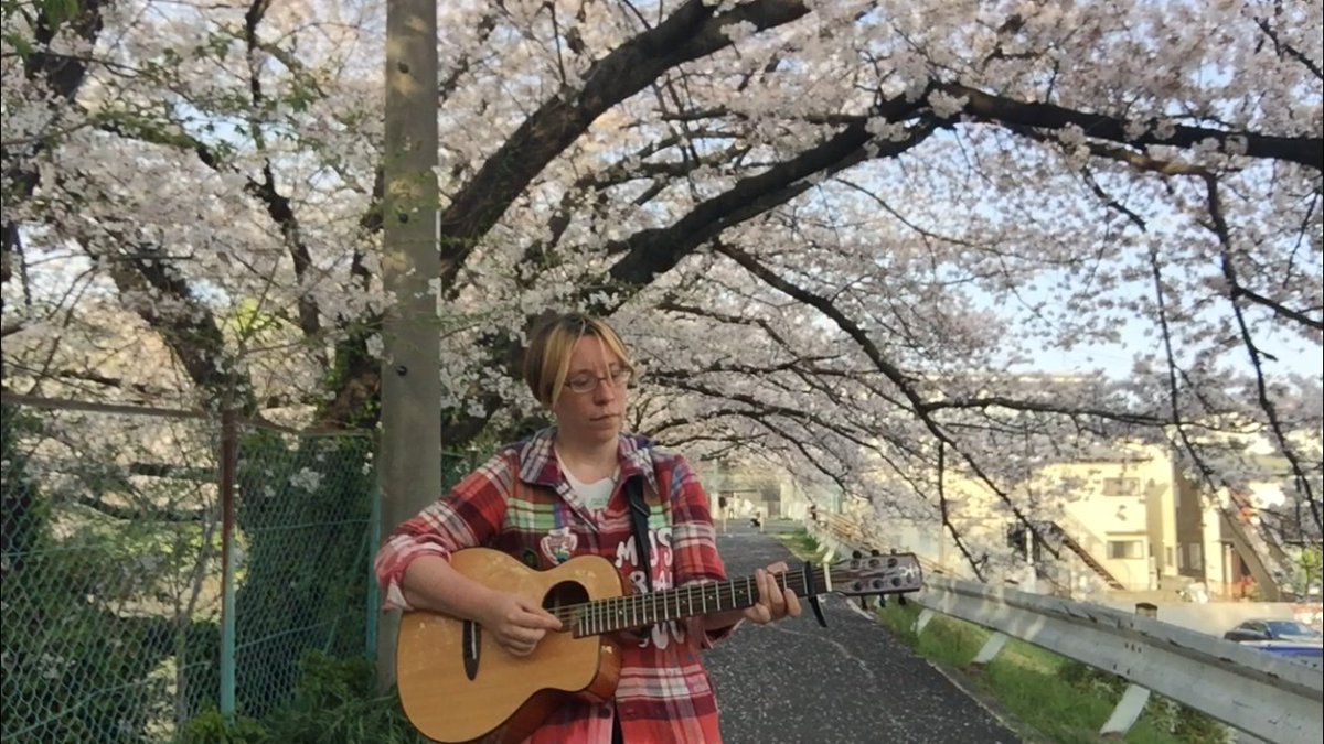 A screenshot of me playing acoustic guitar under an archway of cherry blossoms <3