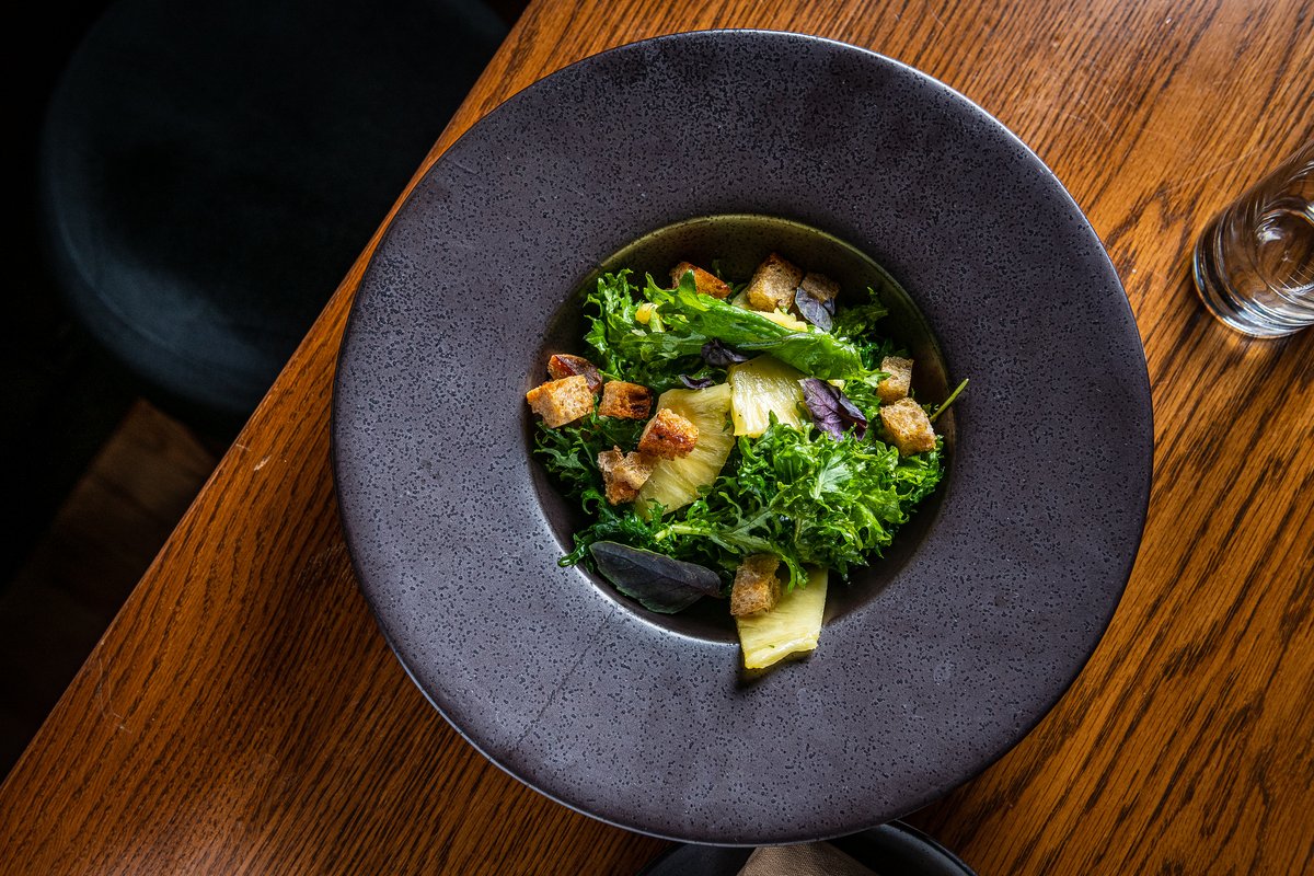 Pineapple and Kale salad with stracciatella, croutons, and a sherry vinaigrette.