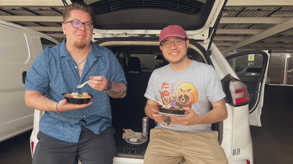 Two guys eating their poke in the trunk