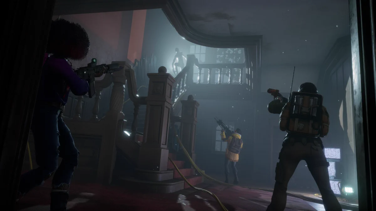 Image from Redfall set in a lived-in mansion that’s fallen into disrepair with a backlit vampire at the top of a wooden staircase with three heroes with their weapons at the ready staring up from the base of the stairs. 