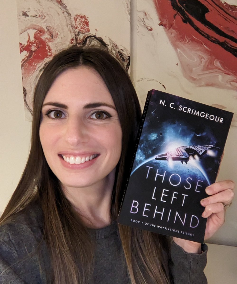 Author N. C. Scrimgeour holding a copy of her book, Those Left Behind, which features a spaceship on a blue space background.