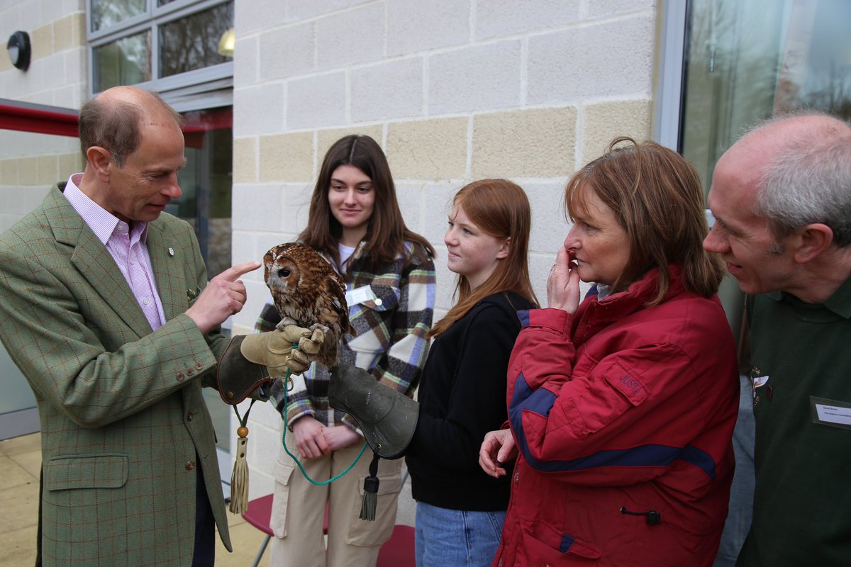 The Duke, holding an owl whilst standing with young people outside at a DofE Open Award Centre.