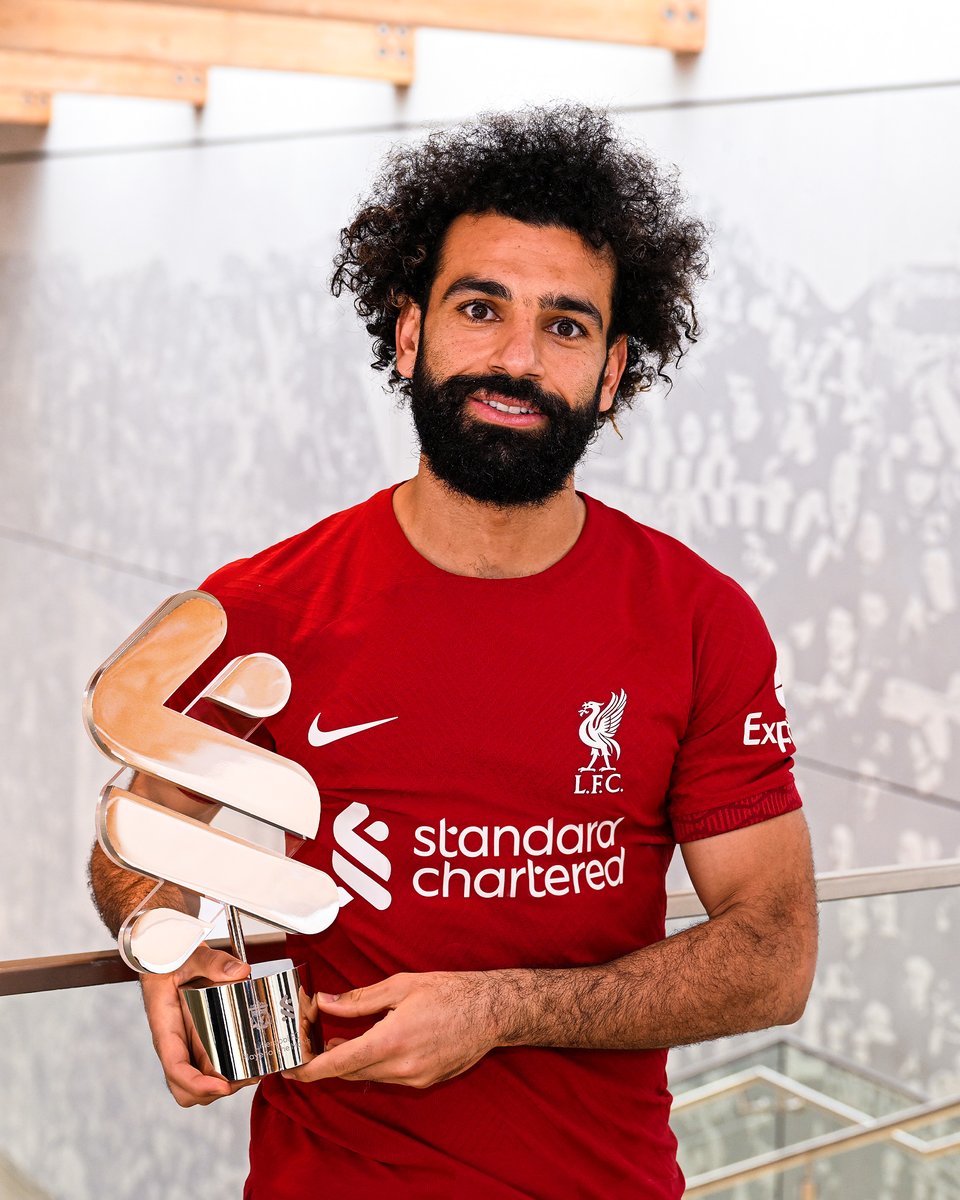 Mo Salah is pictured in the home shirt holding the Standard Chartered Player of the Month trophy for March. 