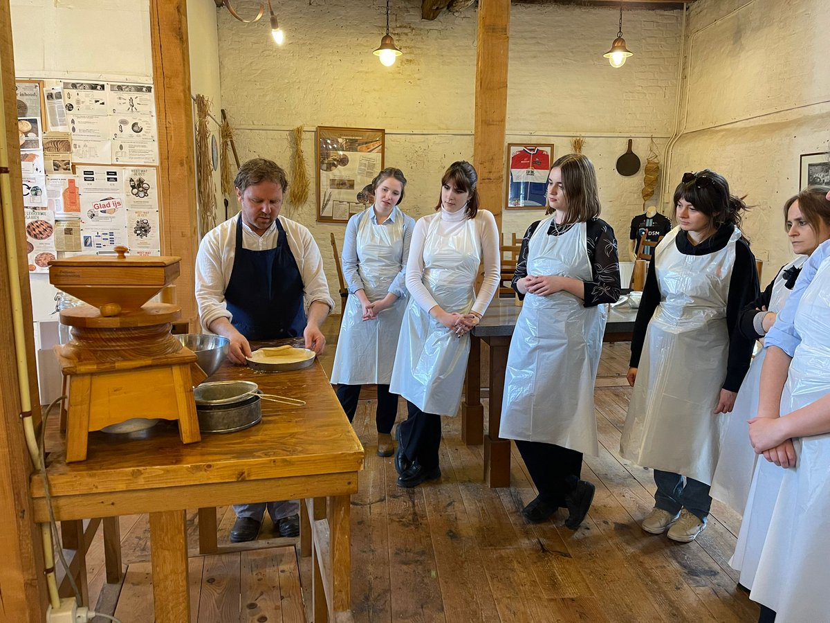 ICCC_2023's tweet photo. Workshop baking flans ("vlaaien"). The master baker explaining how the dough should be put into the form. Participants try to get the idea. https://t.co/U9ReuvgS7b