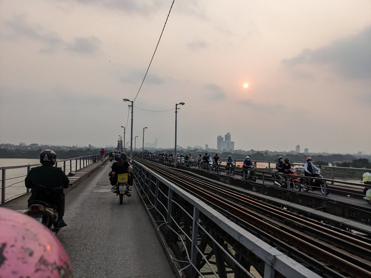DerekRileySC's tweet photo. Afternoon reverse commute heading into Hanoi on the no-cars Eiffel Tower Bridge (Debi on the yellow-trunk bike). https://t.co/RlySivVuvg