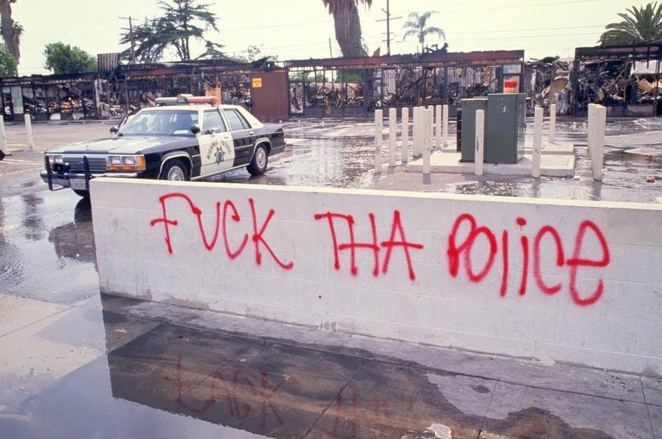 "Fuck that police" painted on a low wall with red spray paint 