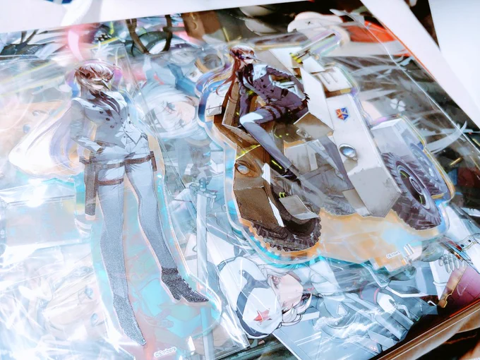 おい待て待てちょっと待て オーロラレインボー福利厚生アクスタがクソでかい A4サイズ公式本の上に置いてこれだし手のひら広げて指先はみ出そうなぐらいデカい アシュアくん?????