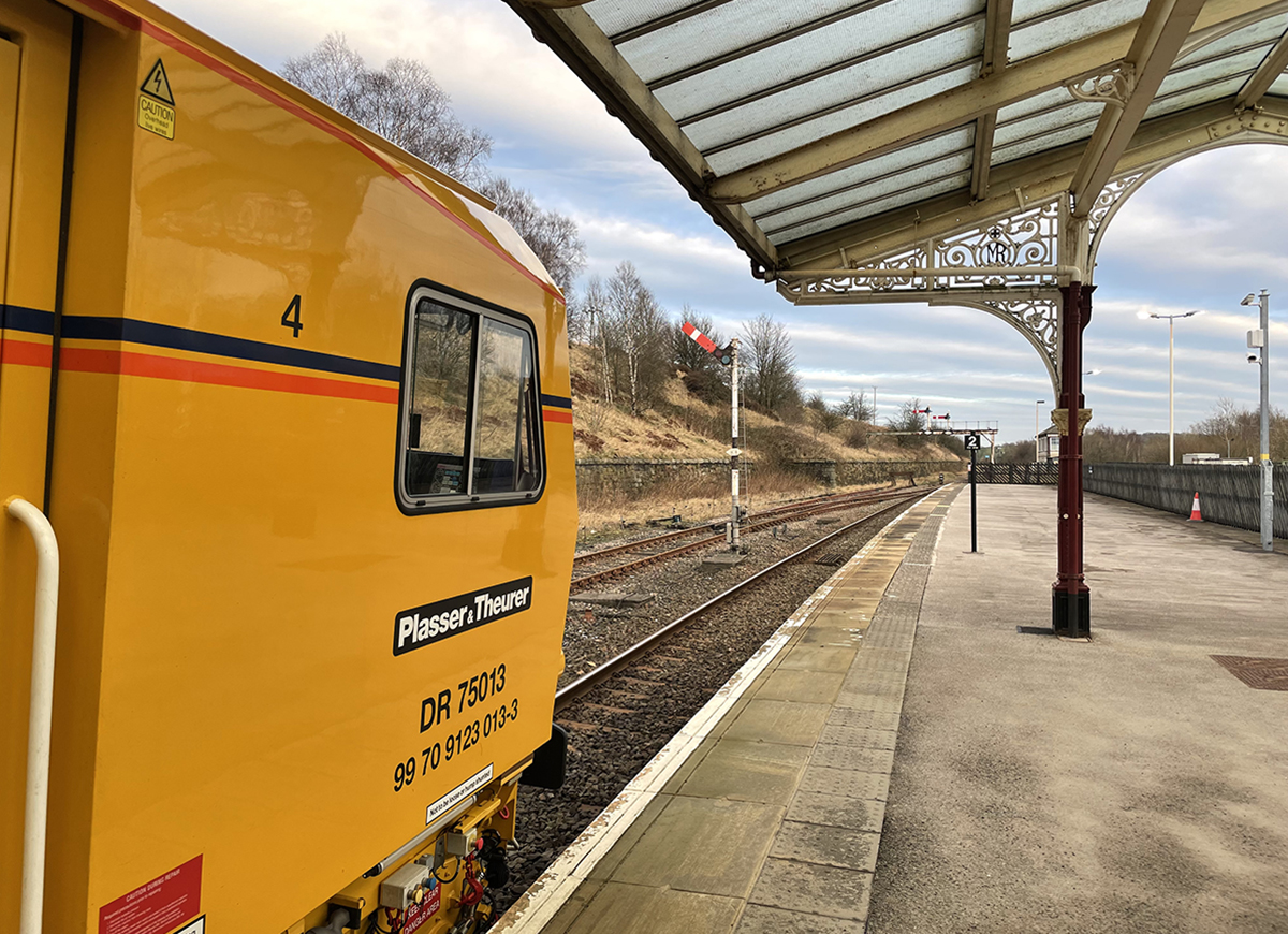 NowtbutaLad's tweet photo. A Plasser UK rail tamping unit waits at #Hellifield in #Yorkshire, February 2022 [my pic.]; the ornate Midland Railway platform canopy still intact but the track in the bay (right), once for trains to #Blackburn #Lancashire via the @RValley_line, is long gone. @RAIL #Railways https://t.co/eOBPq9x5NW