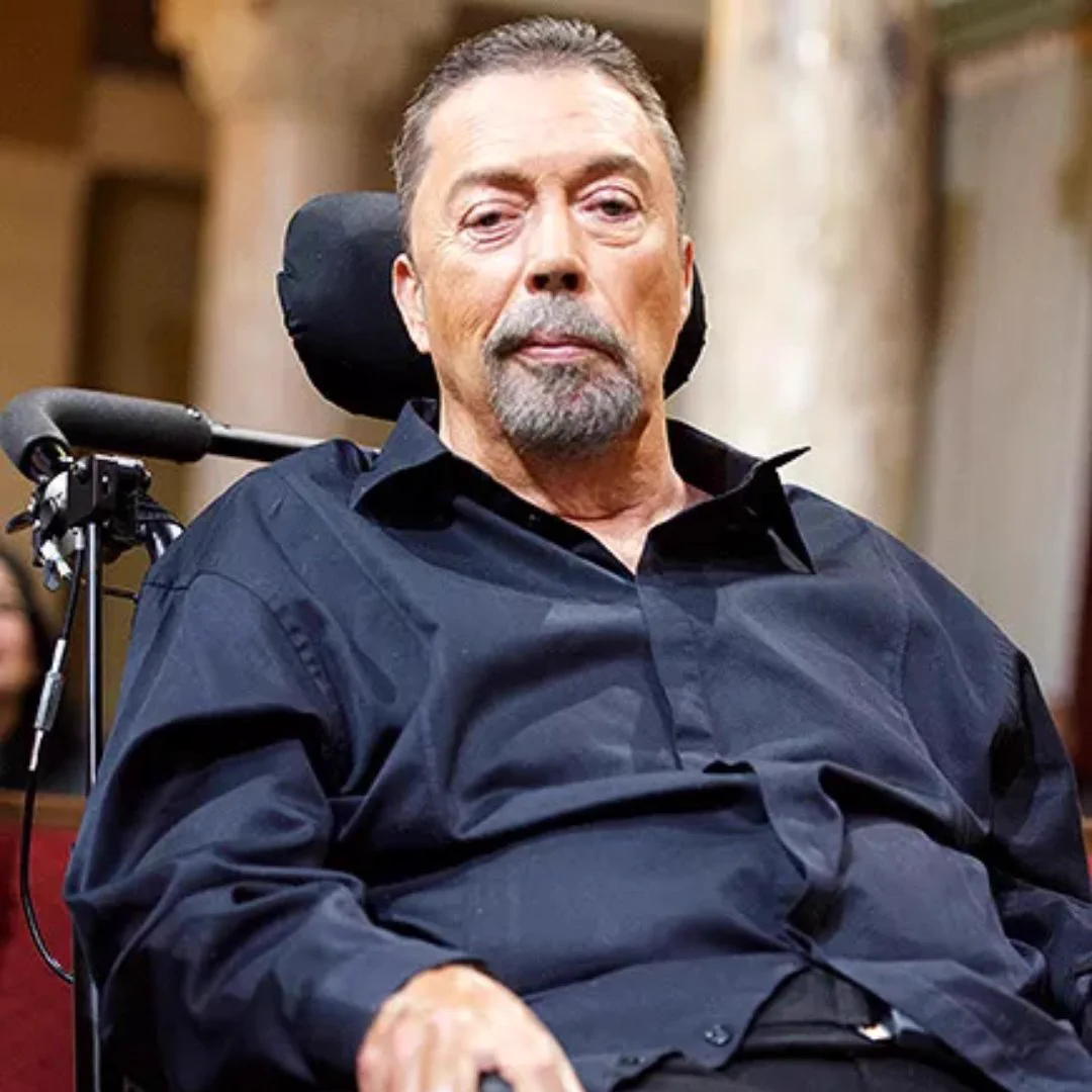 Actor Tim Curry in a dark navy shirt looking at the camera. 