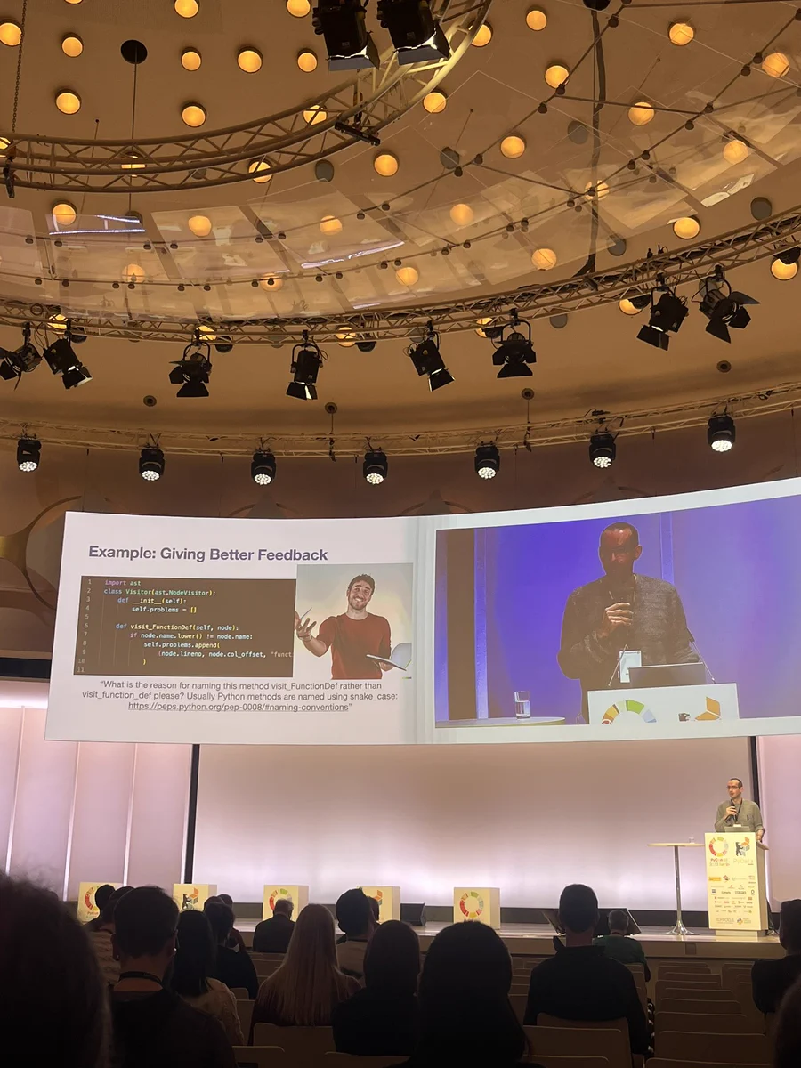 A person giving a talk together with a slide. On the slide: a code snippet with some feedback formulated as a question.