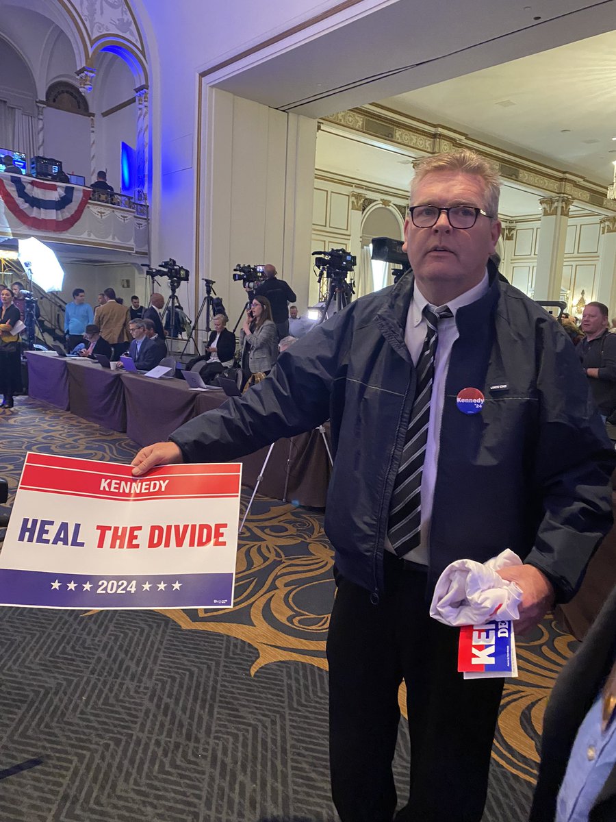 Hundreds of people are crowding into the Boston Park Plaza to see Robert F. Kennedy Jr. announce his bid for the Democratic presidential nomination. No signs of Kennedy family, who have rejected his anti-vaccine movement and his campaign, but many people are holding these signs.