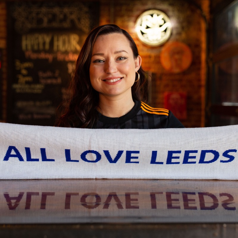 PLinUSA's tweet photo. Wearing your club's kit under your work clothes to demonstrate your passion? That's a tradition we can get behind 👕

Meet @beckycllns88, a @LUFC fan and pharmacist in Fort Worth, Texas, who turned tweets about her favorite @ussoccer players into #PL fandom.

#PLFansofAmerica