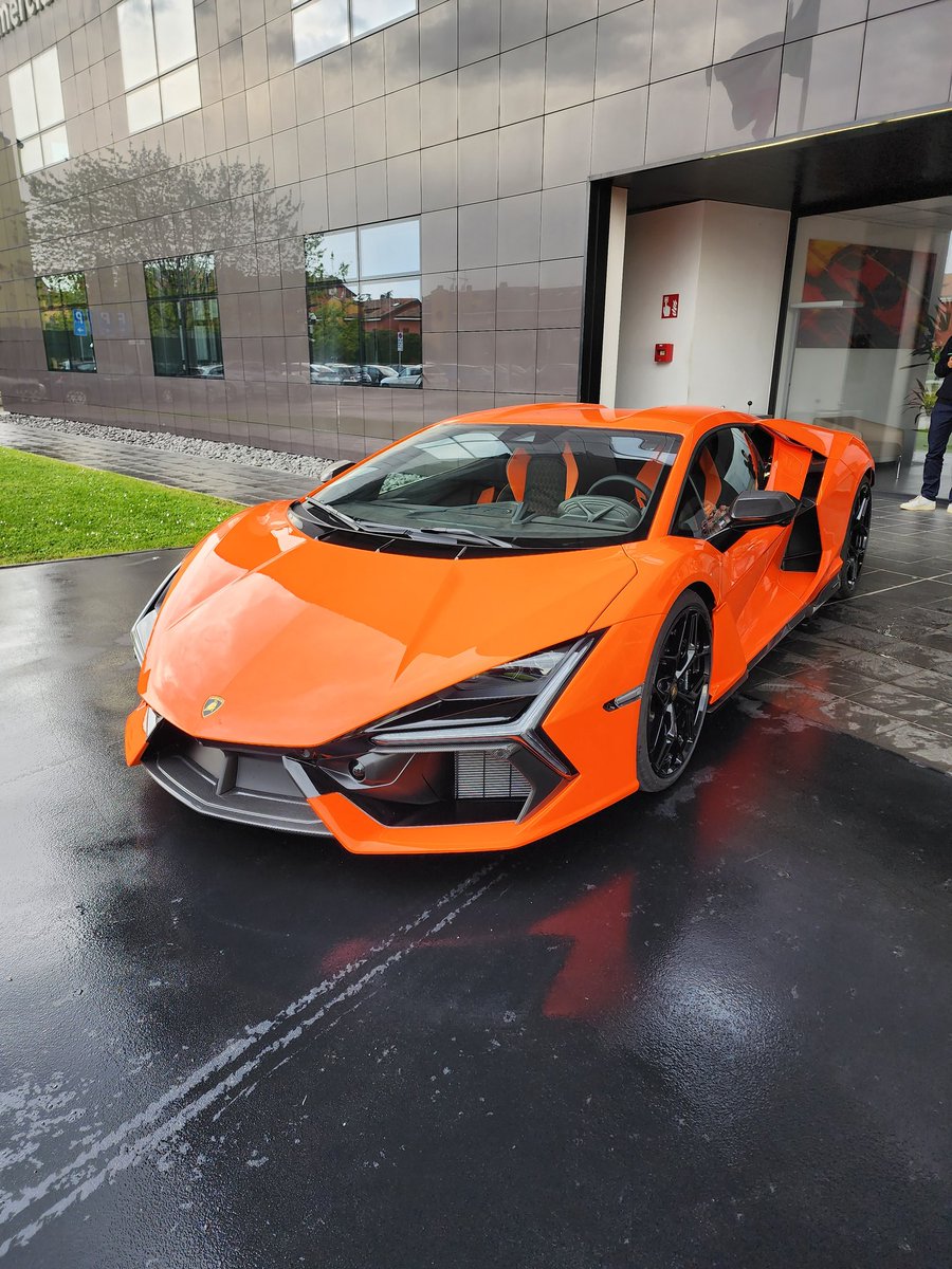 Tim_Stevens's tweet photo. The 1,001-horsepower @Lamborghini Revuelto in the flesh, the company's first plug-in hybrid V12. It's pretty stunning and this orange is perfect. Sadly, the S22 Ultra camera just isn't doing it justice. https://t.co/uoeuKhGZkx