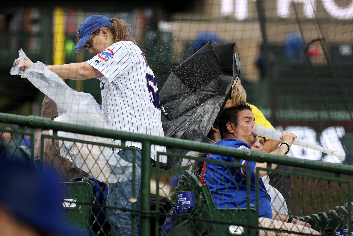 A fan takes a swig of beer from a baseball bat style vessel while dealing with incoming rain that delayed the start of a game between the Chicago Cubs and the Los Angeles Dodgers at Wrigley Field in Chicago on Thursday.
