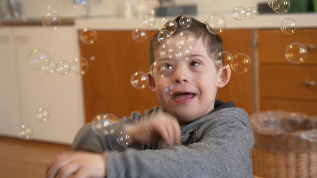 SRF's tweet photo. «Um nichts in der Welt würde ich das zusätzliche Chromosom wieder hergeben», sagt Olga Jappert Vonmoos. Ihr Sohn Janusch kam mit Downsyndrom zur Welt und hatte keinen leichten Start ins Leben. #SRFReporter besucht die Familie ein zweites Mal. #SRFDok https://t.co/0DPItg7nRZ https://t.co/IV3pRS66Kt