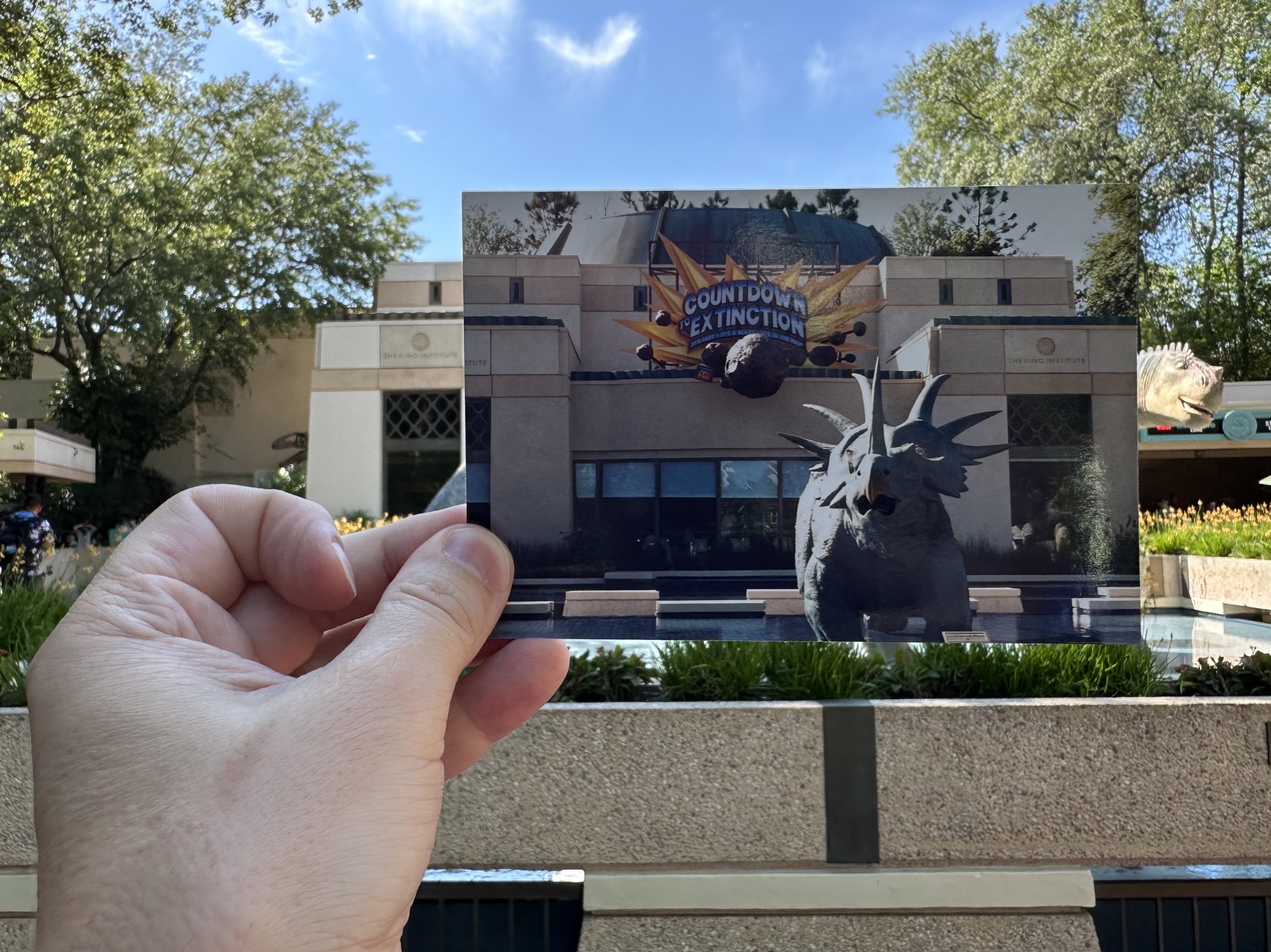 Person holding up a printed photo of the entrance to DINOSAUR! at Disney’s Animal Kingdom