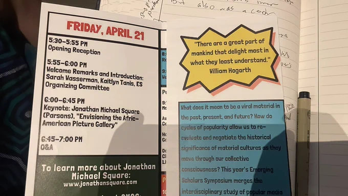 Picture of open conference brochure, sitting on my notebook. Pen on right. Fabric from Em’s dress on left. Brochure reads Friday April 21, 2023 
Left panel: 
5:30pm Opening Reception 

5:50pm Welcome Remarks and Introduction

6:00-7:00pm Keynote Address by Prof. Jonathan Michael Square: “Envisioning the Afric-American Picture Gallery”
To learn more about Jonathan Michael Square: https://www.jonathansquare.com/
Right panel 
 Quotation by Williams Hogarth: “There are a great part of mankind that delight most in what they least understand”
What does it mean to be a viral material in the past, present, and future? how do cycles of popularity allow us to re-evaluate and negotiate the historical significance of material culture as they move through our collective consciousnesses? This year’s Emerging Scholars Symposium merges the interdisciplinary study of popular media [image cuts off text]