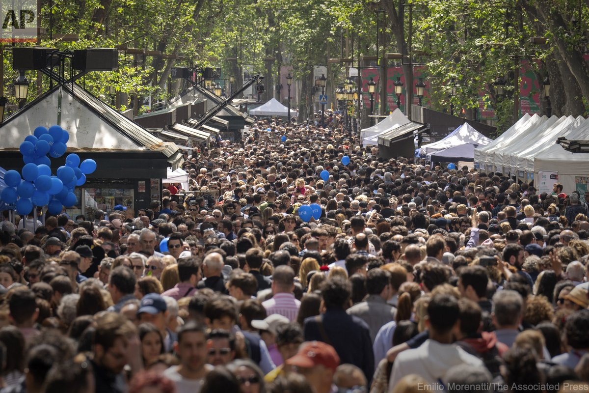 People crowd along the historic La Rambla promenade of Barcelona to buy books and roses at makeshift stands as Catalans celebrate the day of their patron saint San Jordi, Spain, Sunday, April 23, 2023.