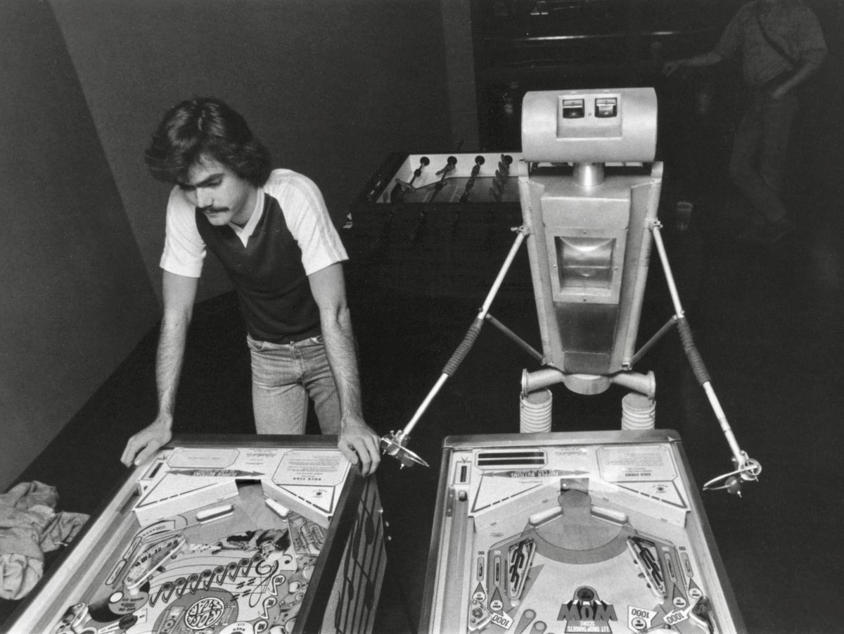 HumanoidHistory's tweet photo. Man and robot play pinball, Green Bay, Wisconsin, ca. 1979. https://t.co/wTyobJsP7A