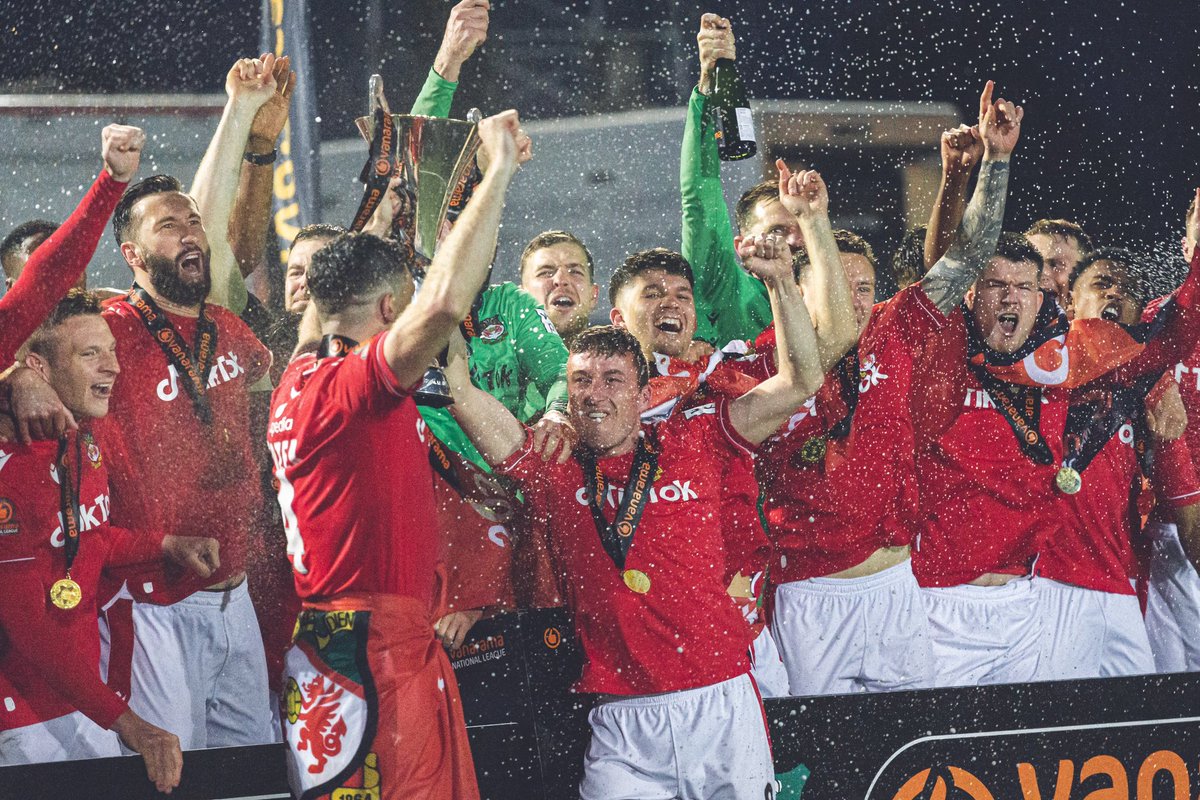 Luke Young and Ben Tozer lifting the National League trophy, with the squad behind them celebrating