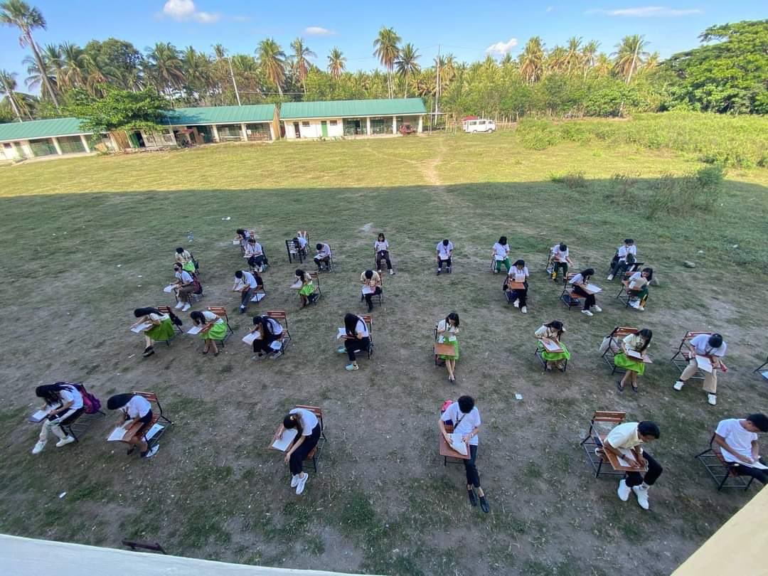 Philippine_live's tweet photo. قال المعلم جويل كاسونغكاد إنه جعل يأخذون إمتحانهم في المنطقة المظللة من الساحة لتقديم تجربة مختلفة للطلاب كما أن المساحة الواسعة والمسافة بين كراسي الطلاب منعتهم أيضًا من نسخ إجابات بعضهم البعض https://t.co/eZOyPVdBSo
