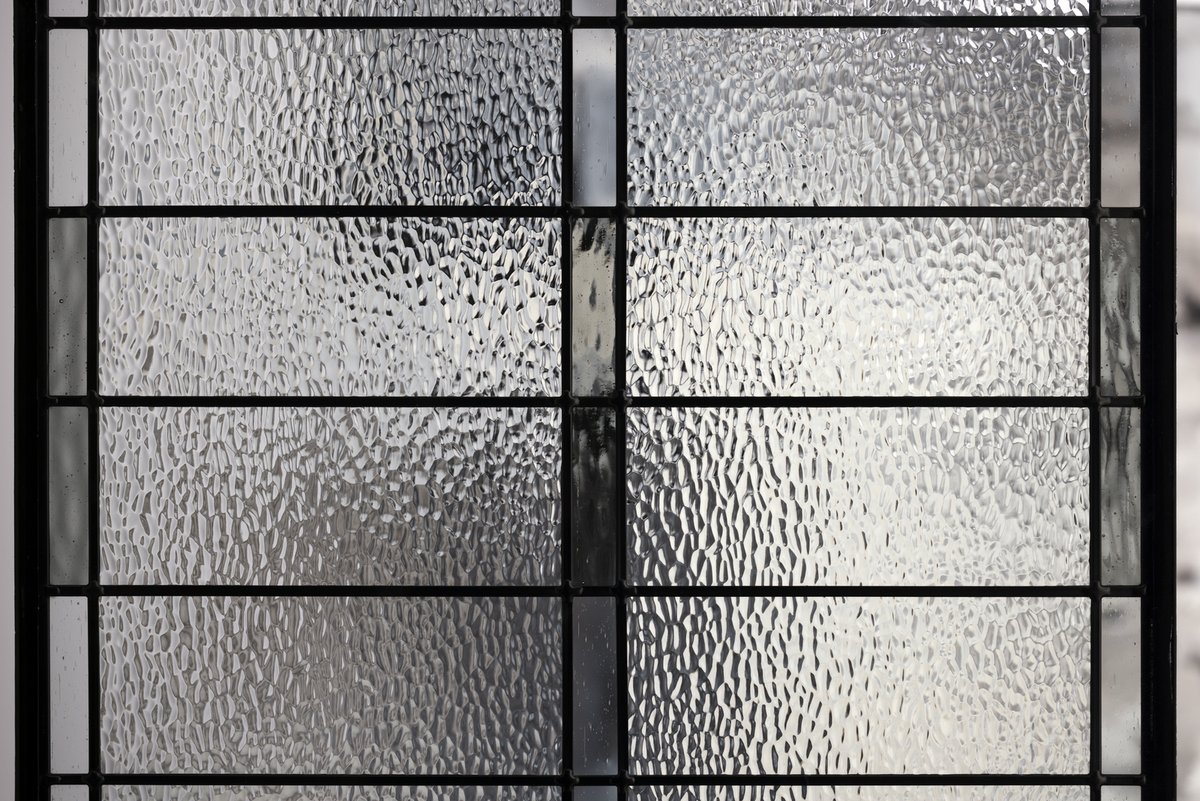 Panels of bold hammered texture in Bay Point create a medium level of privacy interspersed with eye-catching patina caming and accents of clear seedy and gray bubble glass to welcome visitors inside.