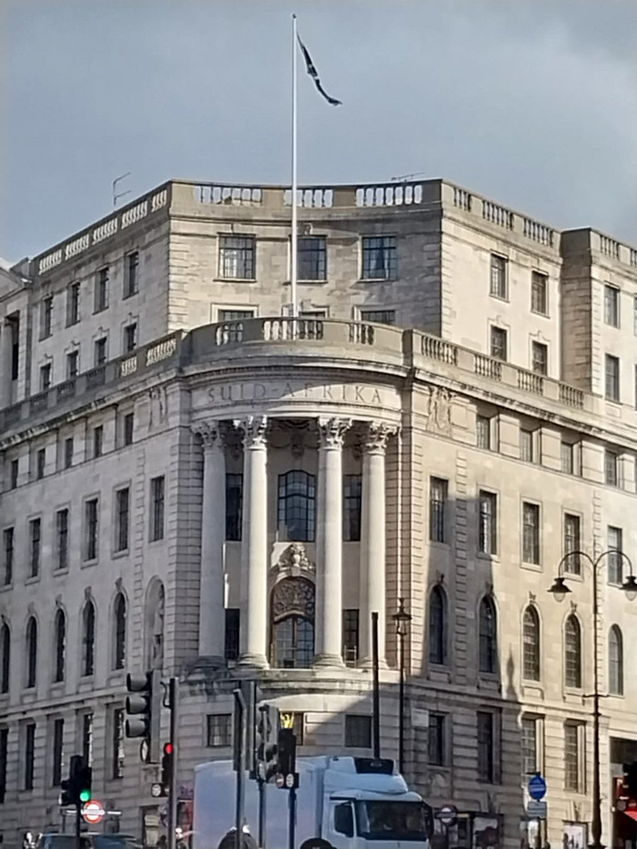 A threadbare South African flag flying above South Africa house in Trafalgar Square, London, hanging in tatters. Appropriate.