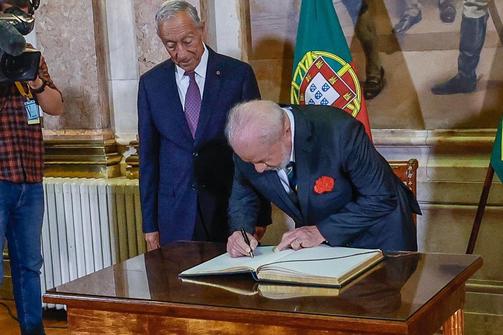 Lula assina livro, enquanto o presidente Marcelo Rebelo de Sousa observa