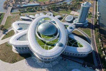 This is the Sci-Tech Complex, a great temple of learning for all the people and a multi-functional hub of scientific and technological dissemination. It is on Ssuk Islet in the capital city of Pyongyang.
  The exterior of the complex is in the shape of a large atomic structure symbolizing the world of science.
  The pen-shaped tower symbolic of science and technology, the sailboat-shaped lodgings, the open-air sci-tech exhibition ground and the fountain park are in good harmony with the complex.