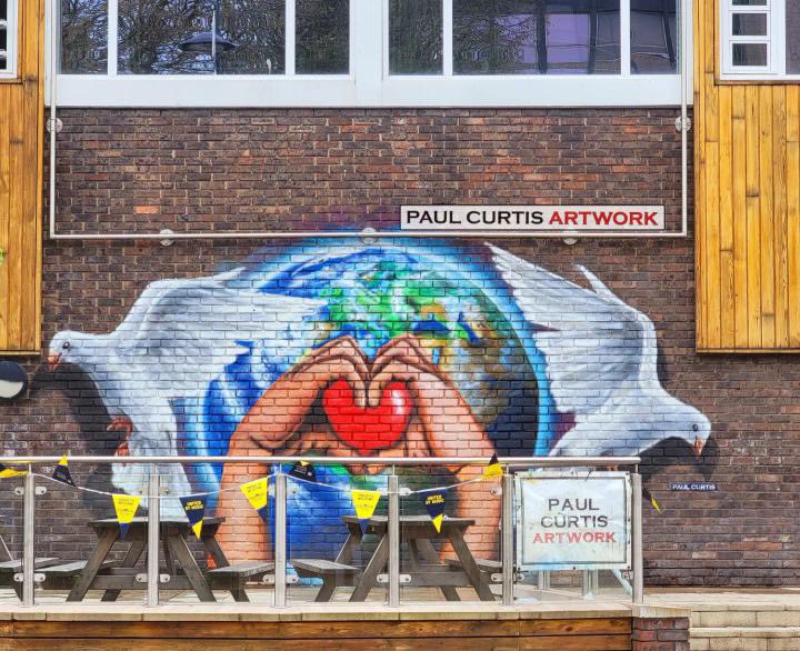 A piece of Eurovision we can keep 🫶✨🪩 @PaulCurtisArty has been hard at work to create an incredible Eurovision mural celebrating peace, love and unity right here on campus ✨🫶🕊️ Pop over to Guild Walk to see the incredible piece yourself ✨