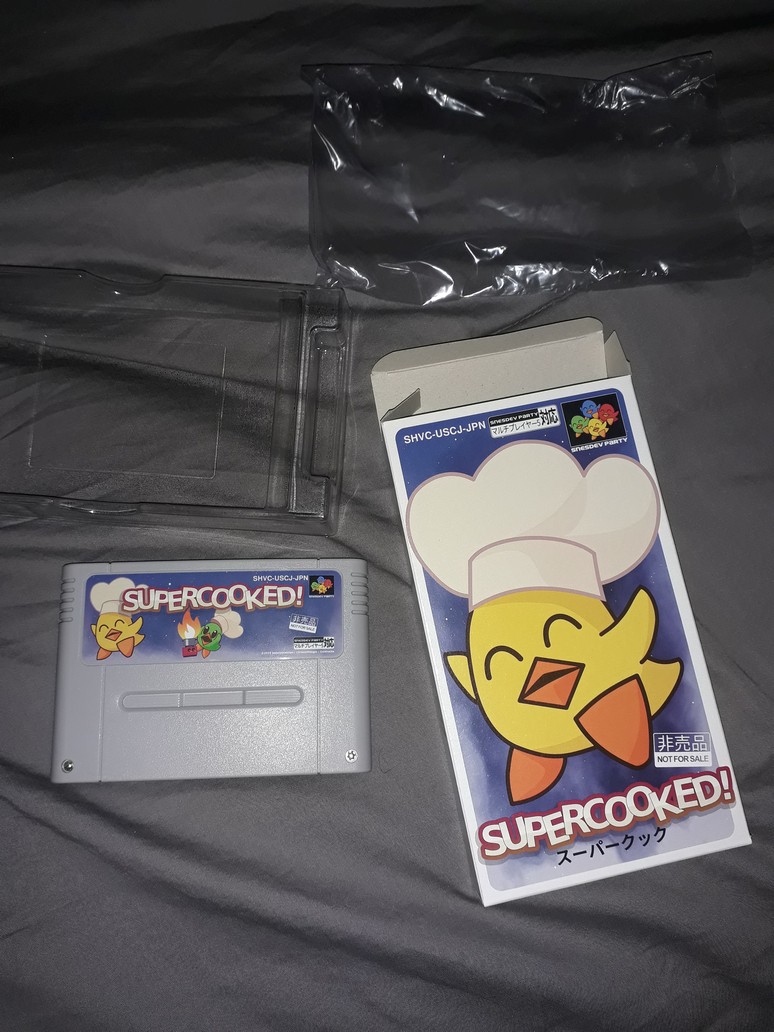 bbbradsmith's tweet photo. Supercooked! A new SNES game by @Goldlocke7. I'm looking forward to playing this.

Wonderful package. The cartridge has real screws, and a simple 5V flash board inside.

Free ROM download: https://t.co/VNM4wVTMF8 https://t.co/8WxFSOT96X