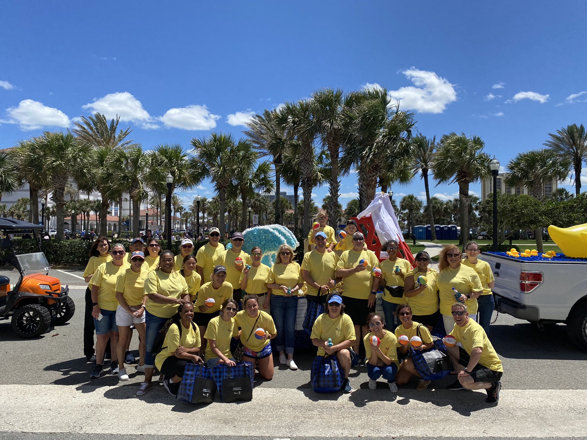 Baptist Beaches team members wearing yellow tshirts standing in front of the parade float they created