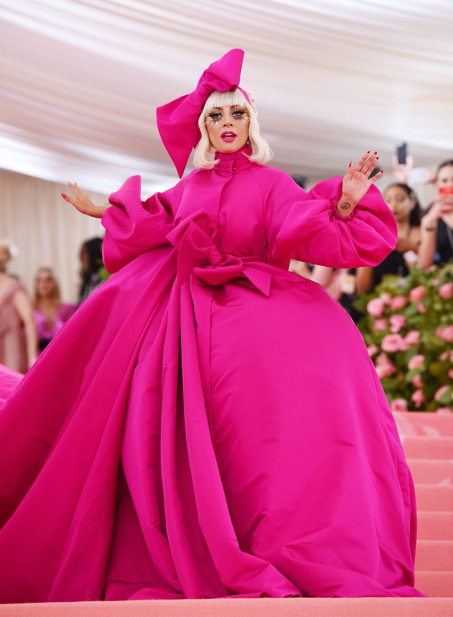gagadaily's tweet photo. VOGUE has ranked Lady Gaga’s epic 2019 Met Gala entrance among the best #MetGala beauty looks of all time:

“Heralded as the Queen of Camp, Lady Gaga did not disappoint when she arrived onto the red carpet with a set of gilded lashes and a 25-foot magenta train.” https://t.co/lIT5L16htX