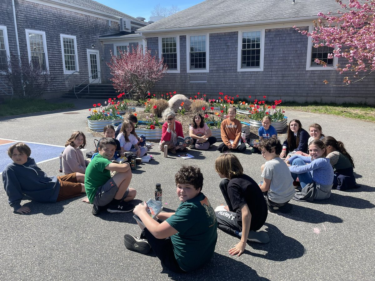 On this fine spring day, grade 5 students and their teacher, Ms. Williams, enjoy reading and discussing Lauren Wolk’s book “Beyond the Bright Sea”.