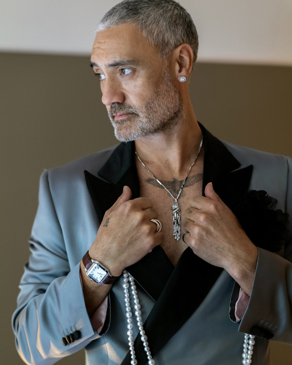 Cartier's tweet photo. In a decisively modern look, @TaikaWaititi combines a Panthère de Cartier High Jewelry necklace in white gold, diamonds, emeralds and onyx with Galanterie de Cartier diamond earrings, a limited-edition Santos-Dumont watch in burgundy lacquer and a #TrinitydeCartier ring. #MetGala https://t.co/QA1qiaSxOQ