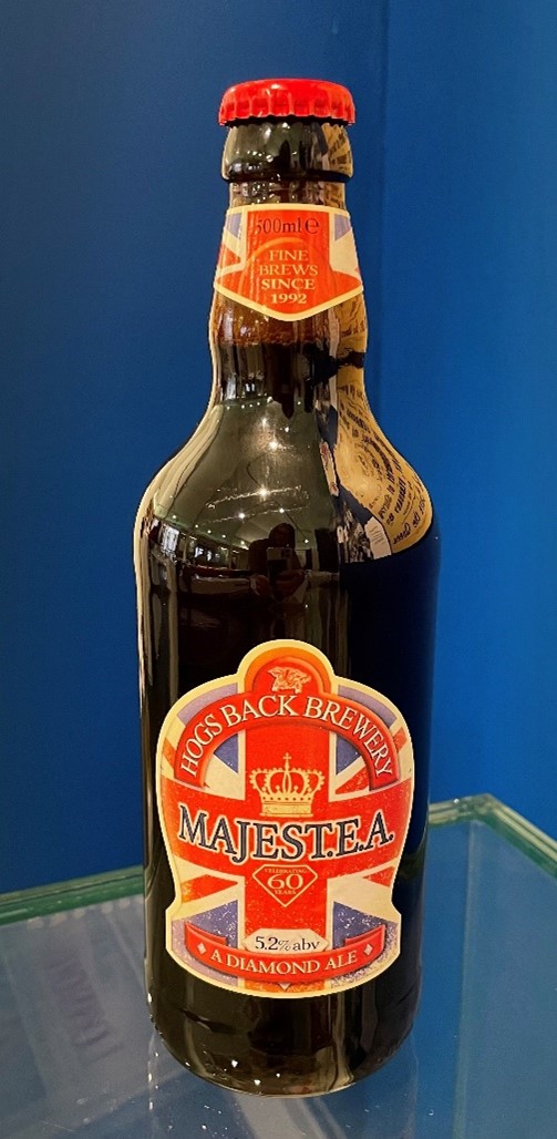 Gfdheritage's tweet photo. Will you be raising a glass to celebrate the #Coronation of King Charles III? This bottle of MajesT.E.A ale was brewed at the #HogsBackBrewery for the Diamond Jubilee of Queen Elizabeth II in 2012. On display in Coins, Crowns and Kings. https://t.co/GwuIxltPFU https://t.co/hyZeFfGWMG
