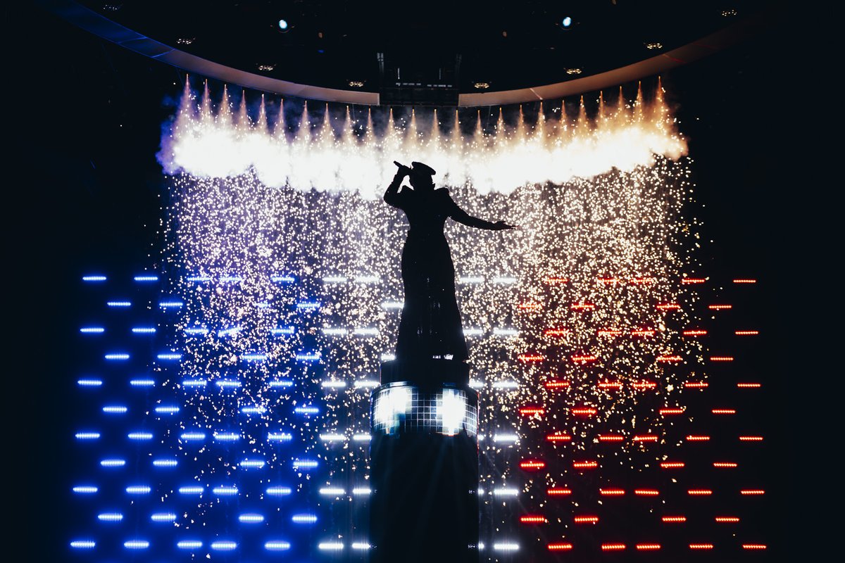 🇫🇷 France - First Rehearsal 'La Zarra standing on top of a sparkle-draped plinth wearing a fitted gown made entirely from black and red sequins.' (eurovision.tv) #Eurovision [📷 Corinne Cumming & Sarah Louise Bennett / EBU]