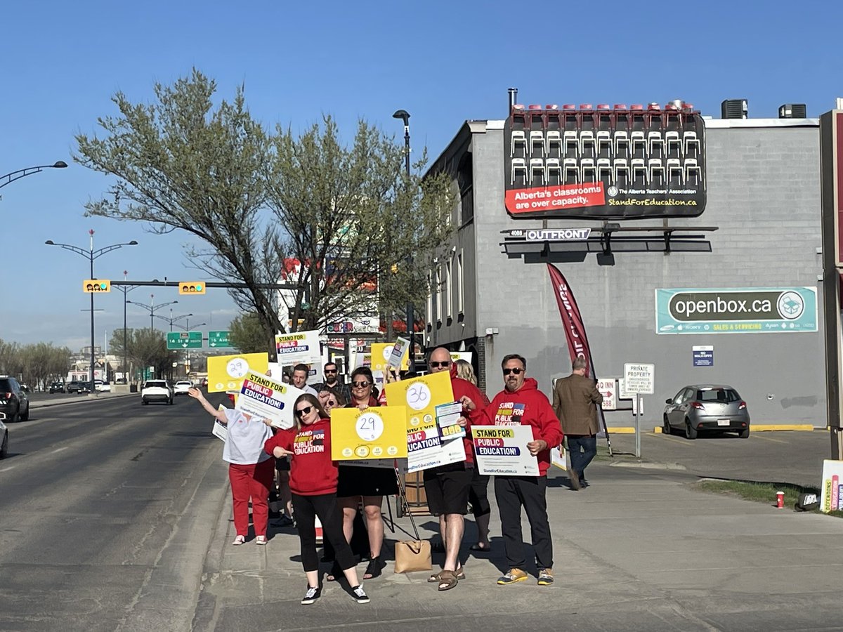 albertateachers's tweet photo. President Schilling &amp; concerned teachers gather at Calgary billboard today to discuss impact of large class sizes on Alberta students. Stand for Education 3-D billboard, with actual chairs mounted on it, highlights classroom overcrowding. Let's unite &amp; demand change. #abed https://t.co/7M3xn1xzyE