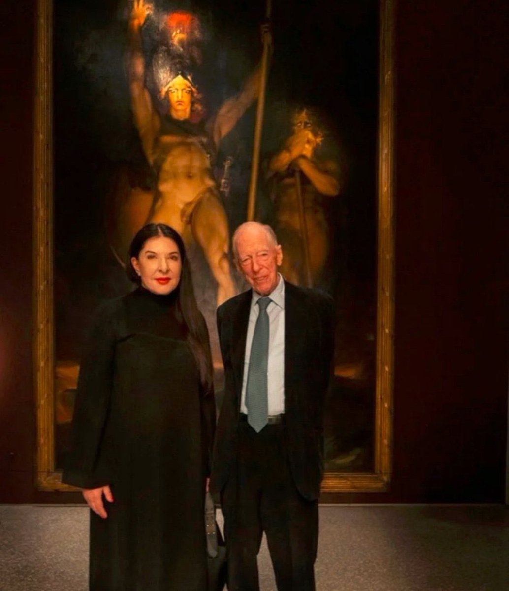 iluminatibot's tweet image. Evil exists in this world.  

Marina Abramovic with Jacob Rothschild standing in front of the painting “Satan Summoning His Legions”
