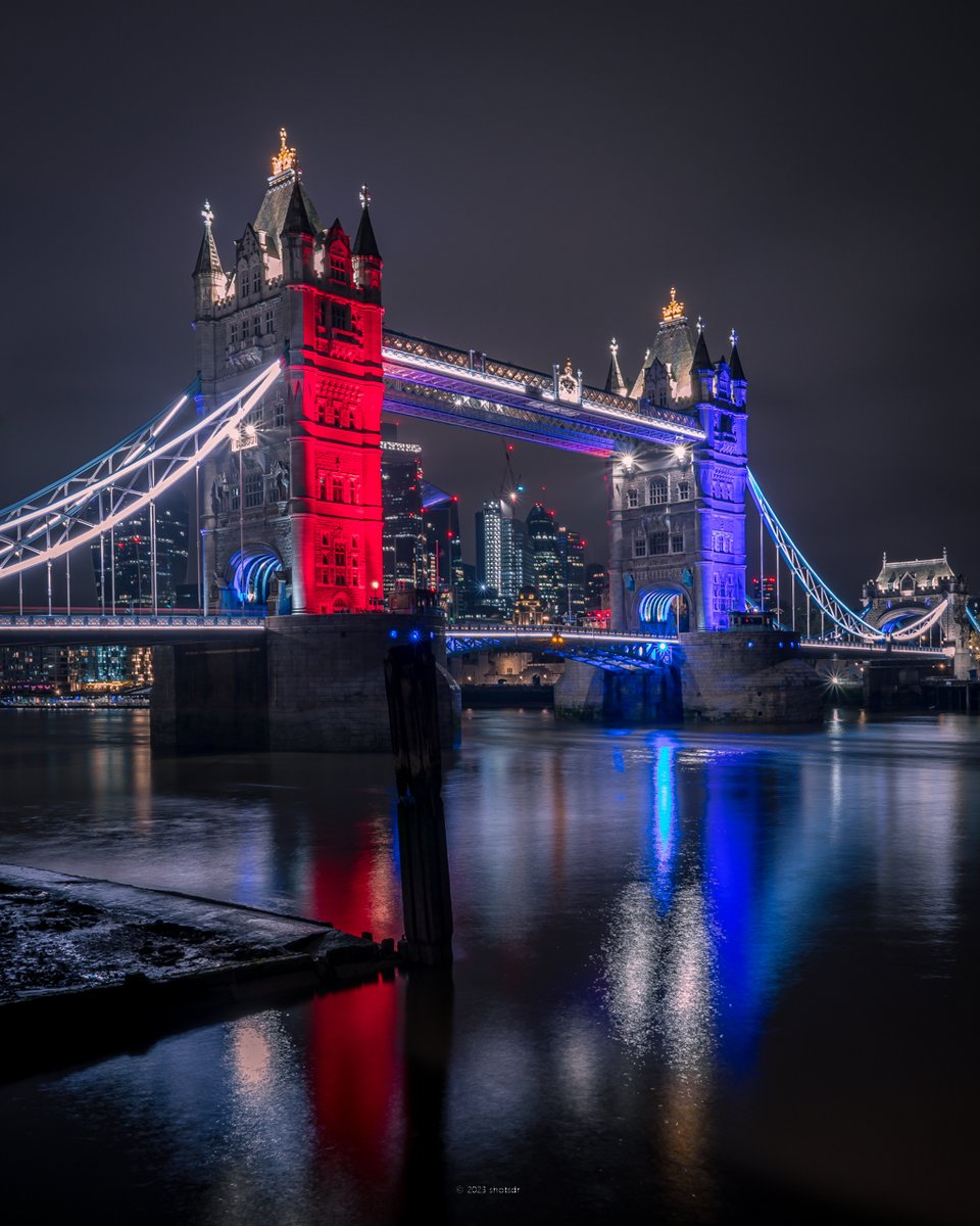 Tower Bridge lit up at night in red, white, and blue for the Coronation