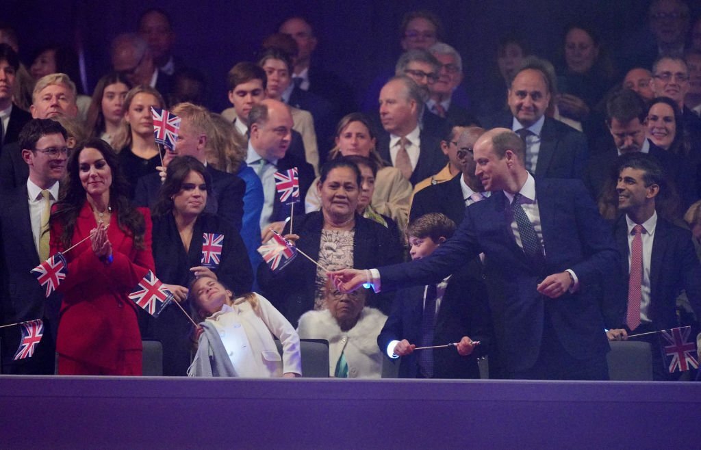 isaguor's tweet photo. Not Prince William putting the flag in prince george and princess charlotte's faces aahahahaha. He is such a dad.

#coronationconcert https://t.co/qB2JFRdabr