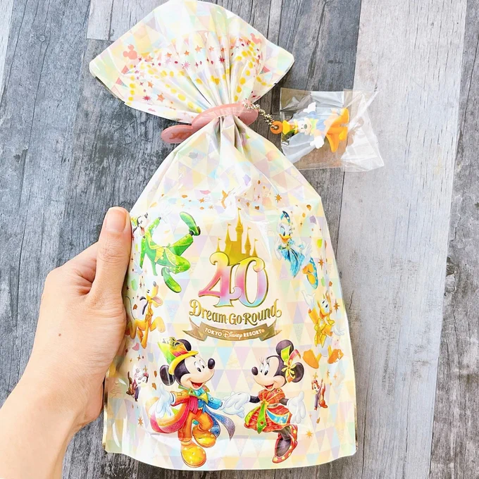 【ディズニーお土産】衝動買いして正解だった…。40周年仕様の「激かわクッキー」キーホルダーも付いてて豪華すぎる!   ディズニー40周年の「チョコチップクッキー」が可愛い!ディズニーの仲間がデザインされた袋にクッキーが10枚入ってるの。キーホルダーも付いててお得!