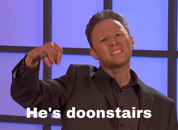 Limmy’s show sketch parodying John Edwards. Limmy in a dark suit and dark shirt, in front of a purple background with black lines, white text saying “He’s doonstairs”.