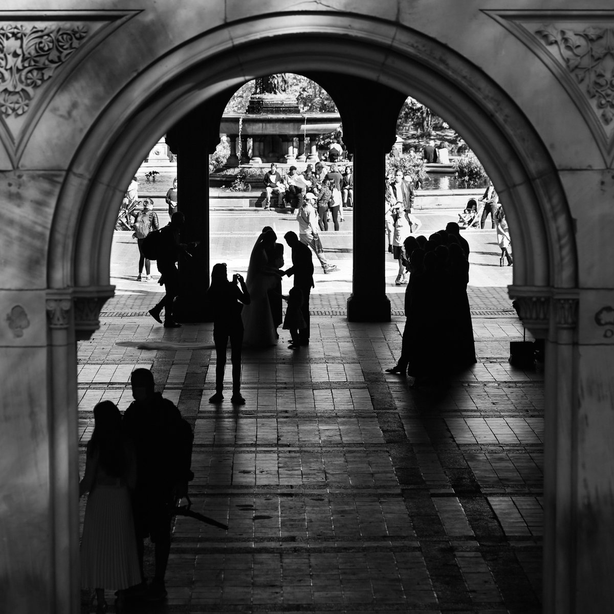 Captured a precious moment through the architectural beauty of #CentralPark. The silhouette of the wedding celebration whispers of everlasting love amidst the city's restless rhythm. The iconic #BethesdaFountain stands tall in the backdrop. #artphoto #photography #artist